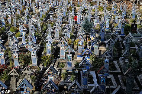Un homme se tient entre les croix peintes dans le cimetière joyeux, à Sapanta, dans le nord-ouest de la Roumanie, le dimanche 10 septembre 2017. Le cimetière joyeux est une collection de plus de 1000 croix orthodoxes vives gravées d'épitaphes colorés et de dessins enfantins et, malgré ses endroit éloigné, à environ 600 kilomètres (360 miles) au nord-ouest de la capitale roumaine, Bucarest, c'est l'une des principales attractions touristiques du pays. (Photo AP / Vadim Ghirda)